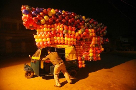 Yeni Delhi’deki bir Pazar yerinde satmak üzere araba şeklinde bir vagona renkli toplar doldurduktan sonra aracı itmeye çalışan bir adam.